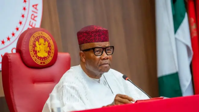 Nigeria senate president Godswill Akpabio wear white Agbada, microphone dey im front.
