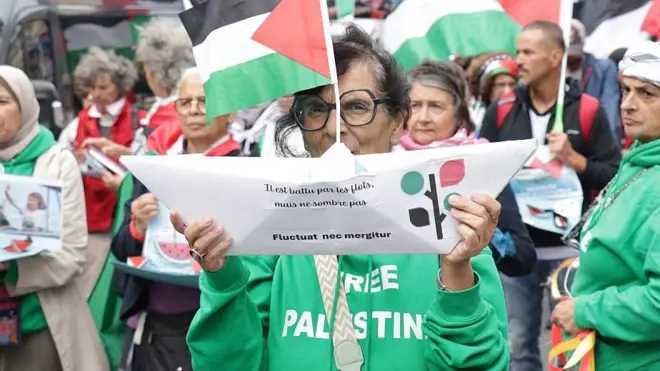 Mujer en una manifestación en París con un barco de papel