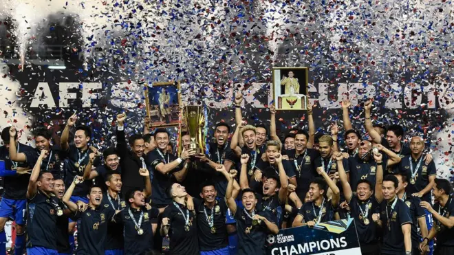 Para pemain Thailand merayakan kemenangan dengan foto mendiang Raja Bhumibol yang belum lama meninggal.