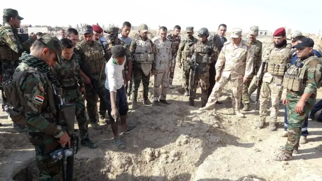 Iraqi forces inspect the site where they say hundreds of bodies have been buried