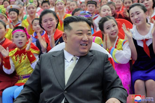 Kim Jong Un with a crowd of young female admirers behind him