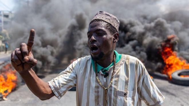 Homem em meio a pneus em chamas no Haiti