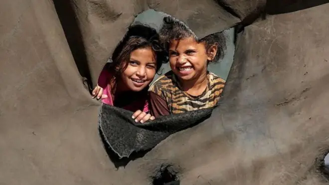 मध्य गाझामधील विस्थापित लोकांच्या छावणीत तंबूखालून मुले बाहेर डोकावताना ( 7 ऑक्टोबरचा फोटो)