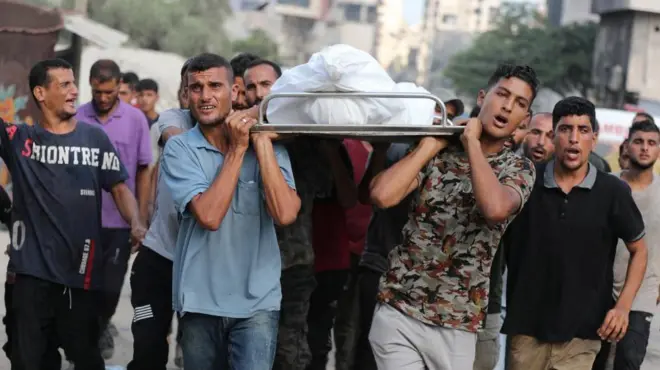 Un grupo de hombres carga un cuerpo durante el funeral por palestinos muertos en un bombardeo israelí.