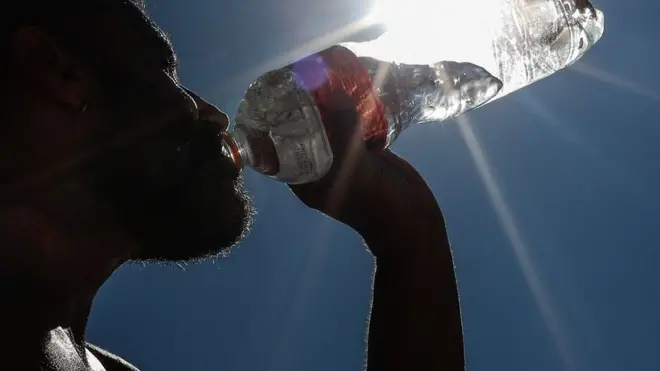 A man drinks water on Copacabana Beach in Rio de Janeiro, Brazil, 19 September 2023, as parts of Brazil faced a heatwave.