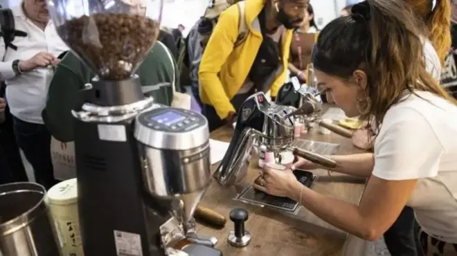 Une femme devant la machine à café avec des gens autour d'elle