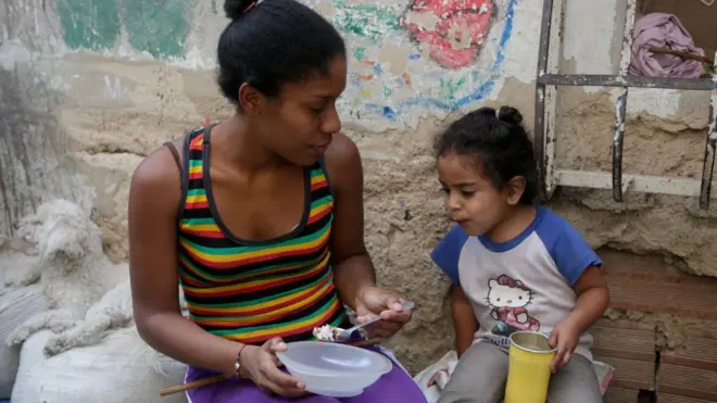 Una mujer alimenta a una niña en el barrio La Bombilla en Caracas.