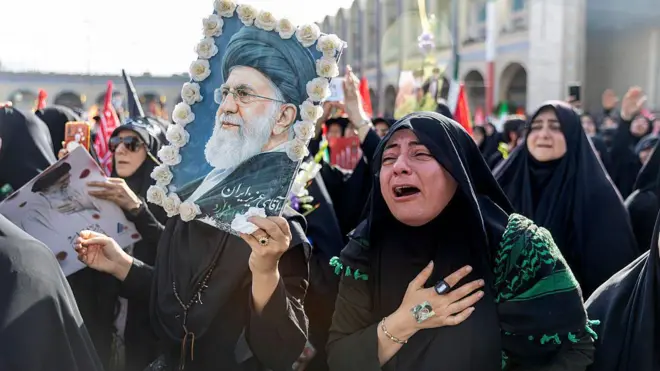 4 Temmuz'da Tahran'da Ali Hamaney'in cenaze törenine katılan kadınlar siyah çarşaflarıyla ve ellerinde Hamaney posteri, bayraklar ve çiçeklerle üzgün bir şekilde ve bazıları ağlarken görülüyor