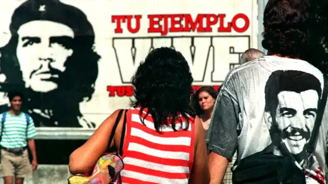 Una pareja camina delante de un mural dedicado al Che Guevara en La Habana.