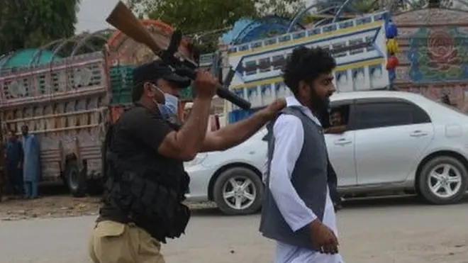 ایک پولیس اہلکار پشاور میں ٹی ایل پی کے ایک کارکن کو گرفتار کر کے لے جاتے ہوئے