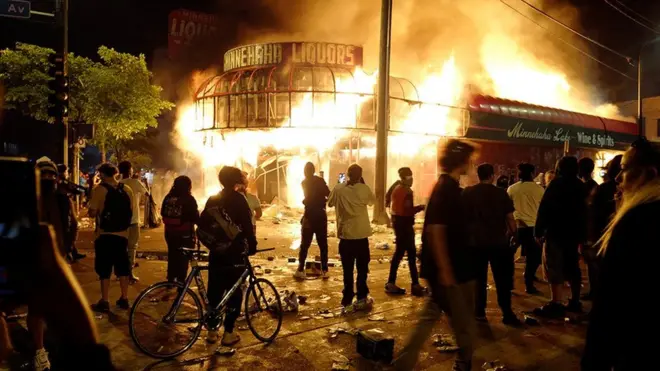 Protesters gather to watch a liquor store burning