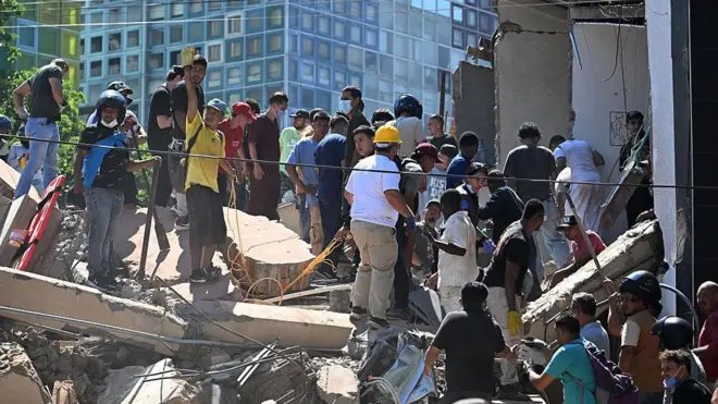 Personas buscan sobrevivientes entre los escombros de un edificio derrumbado en Cali.