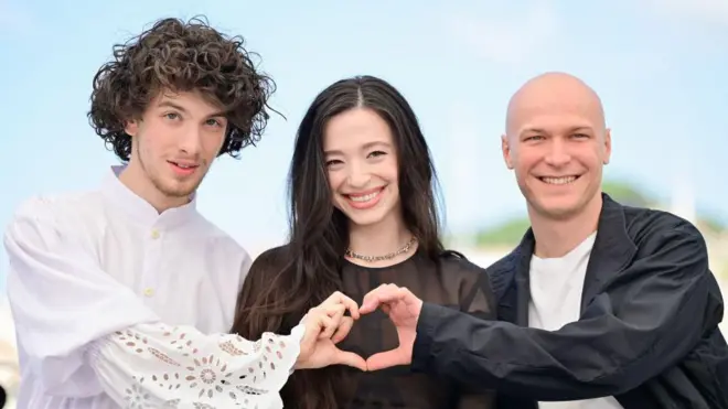 Трое актеров из фильма "Анора": Марк Эйдельштейн, Майки Мэдисон и Юра Борисов. Эйдельштейн и Борисов изображают руками сердечко.