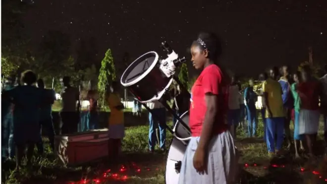Msichana akitazama angani kwa kutumia darubini