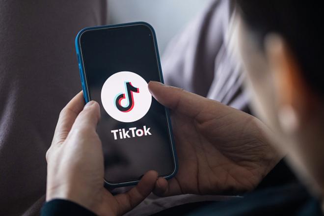 Pessoa3500 jogos online gratiscostas usando celular, que mostra logo do TikTok