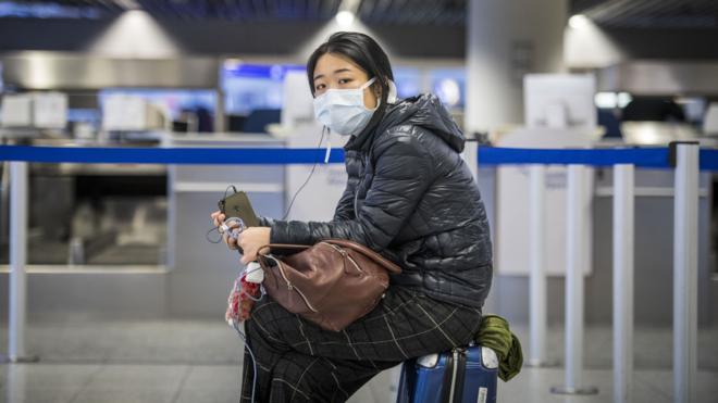 德國法蘭克福機場一位中國女孩在值機櫃台前坐在行李箱上等候（12/3/2021）