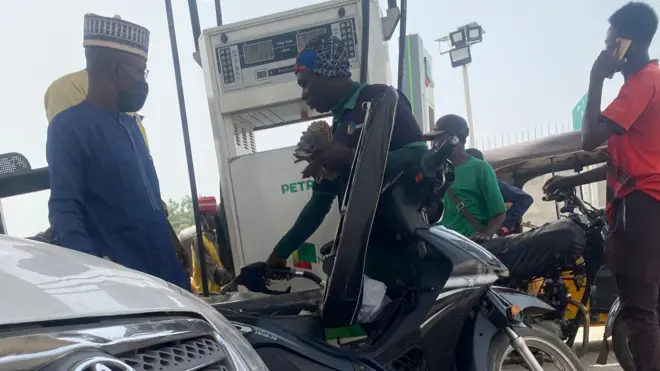 A fuel attendant selling fuel to a motorcyclist