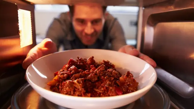 Hombre recalentando un plato en el horno