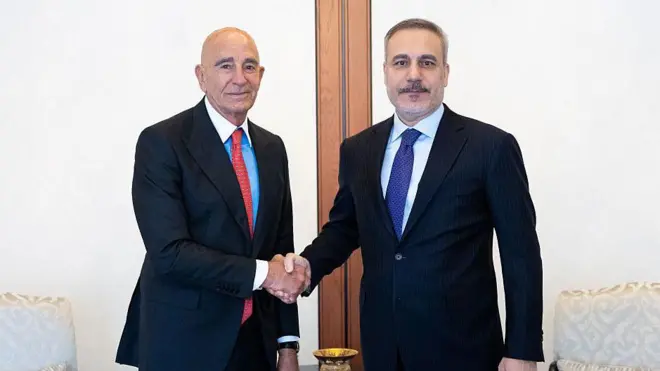 Hakan Fidan ve Amerikalı büyükelçi el sıkışıyor ve kameraya bakıyor.