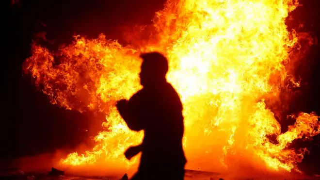 Seorang pria melewati pembakaran pembatas jalan.