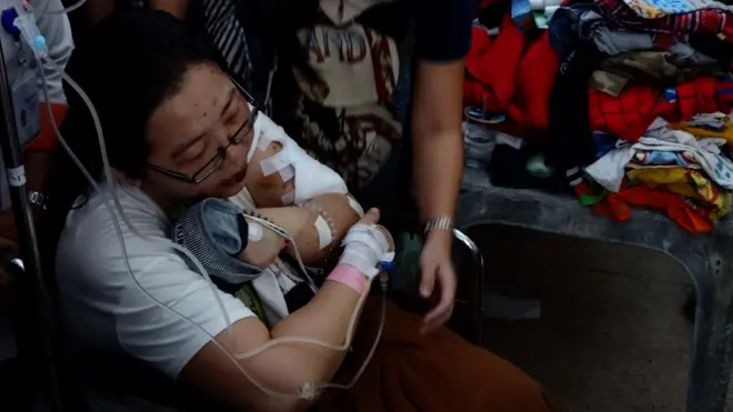 Wenny Hudojo yang masih harus menggunakan infus dan duduk di kursi roda, memeluk baju putranya sebelum prosesi penghormatan terakhir penutupan peti di Rumah Duka Adi Jasa, Surabaya, Rabu (16/5).