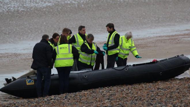 National Crime Agency officers examine the abandoned dinghy