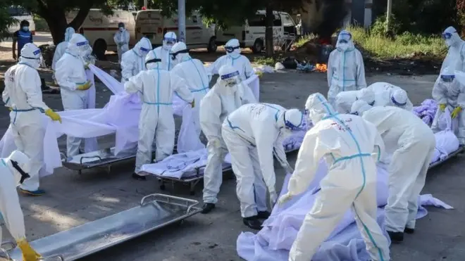 Volunteers wearing personal protective equipment (PPE) arrange bodies of people who died from the Covid-19 coronavirus during their funeral at a cemetery in Mandalay on July 14, 2021.