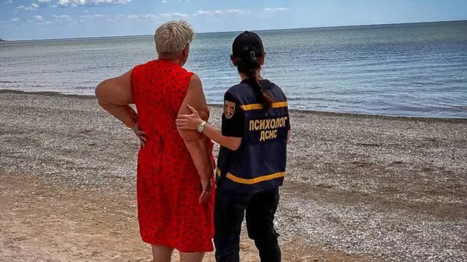 море і пляж, психолог ДСНС тримає за руку жінку, яка вдивляться в море