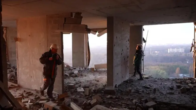 Abagabo 2 barimo kureba uko ibintu byangiritse mu nyubako y’amacumbi yasenyutse muri Kyiv.