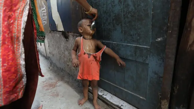 一个逃到印度德里的罗兴亚难民妈妈在喂孩子食物。