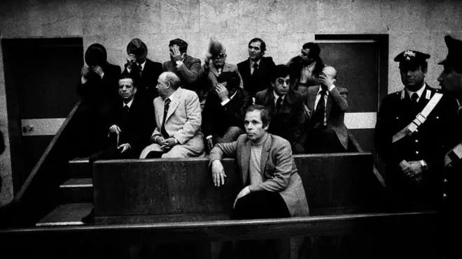 این عکس در جریان دادگاهی در سال ۱۹۷۸ گرفته شده که به "محاکمه ۱۱۴ نفر" معروف شد. دادگاهی‌ که طی‌ آن‌ ۱۱۴ عضو مافیا محاکمه شدند.