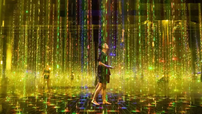 People walk through a large colourful art installation