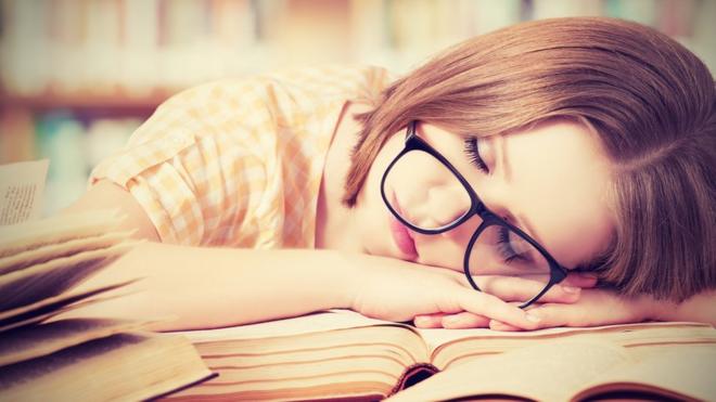 Mujer dormida sobre los libros
