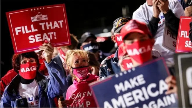 Trump supporters hold a sign telling Trump to fill the seat