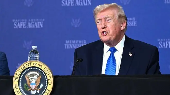 ダークスーツに白シャツ、青色ネクタイを着けたトランプ氏は、米大統領のシールがつけられた演台に立って口を開いている