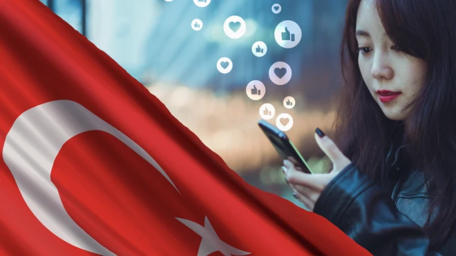 मोबाइल देखतीं एक महिला और तुर्की का झंडा