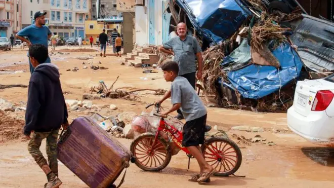 Un niño camina entre el lodo tras las inundaciones en Derna. en