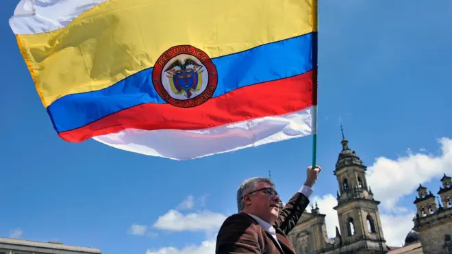 La bandera de Colombia con dos franjas más, una arriba y una abajo, de color blanco, símbolo universal de la paz.