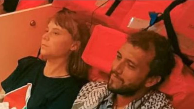 Greta Thunberg y otros activistas sentados en el suelo de un barco apoyados sobre unos chalecos salvavidas.