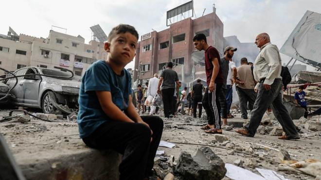 加沙兒童坐在被炸毀房屋前