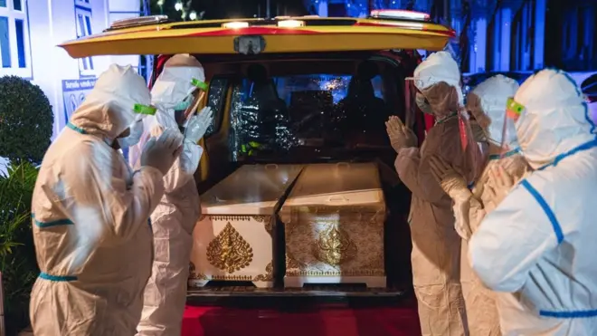 เจ้าหน้าที่ไหว้ศพผู้เสียชีวิตจากโรคโควิด-19 ก่อนพิธีฌาปนกิจ