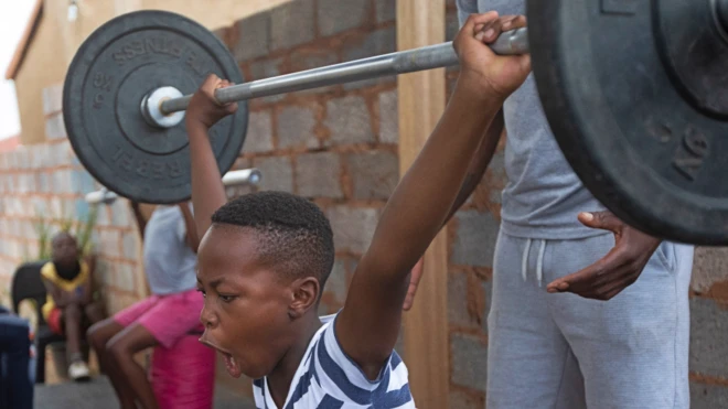 A young boy lifts heavy weights at a training session in Soweto, South Africa - Thursday 27 January 2022