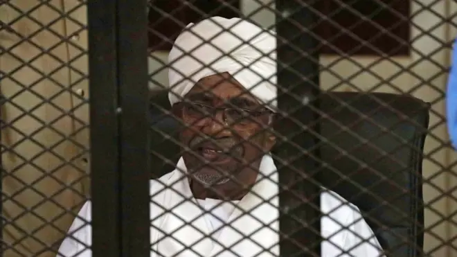 Former president of Sudan Omar al-Bashir, siddon inside cage during im sentencing