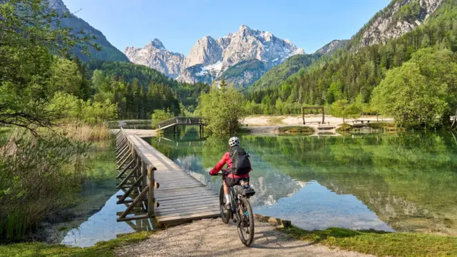 Mulher com bicicleta elétrica de montanha nos Alpes Julianos, na Eslovênia, Europa.