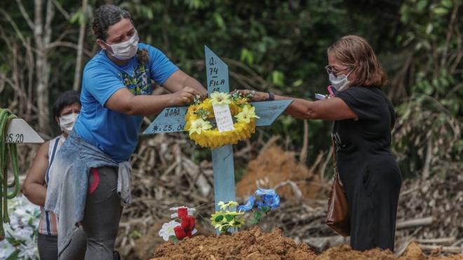 Women put flowers after the burial of a man in Manaus