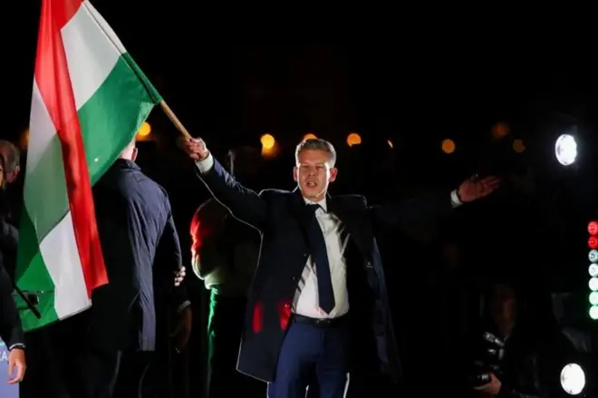 Peter Magyar, con los brazos abiertos y una bandera húngara, celebra su victoria en Budapest. 