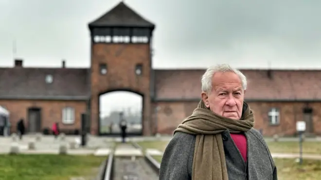 Саймон Шама на фоне главного барака Освенцима