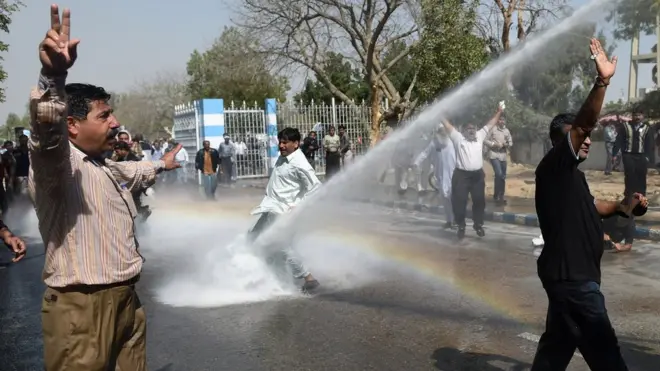 पाकिस्तान के कराची में एक प्रदर्शन के दौरान पानी की बौछार झेलते प्रदर्शनकारी