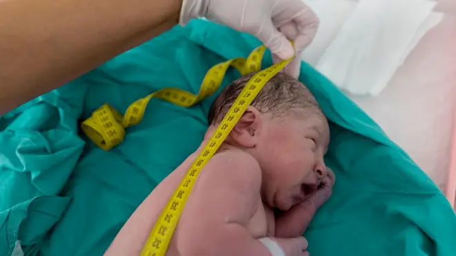 Yeni doğmuş bir bebeğin mezurayla boyu ölçülüyor. 