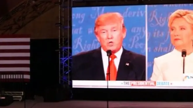 Трамп и Клинтон на экране в зале, где проходили дебаты